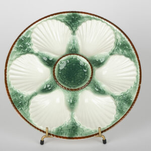 Assiette à huîtres Longchamp blanche à nuances vertes, coquilles en relief et bord brun.