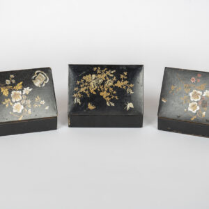 Trois boîtes en carton bouilli noir ouvertes, couvercles à décor floral doré.