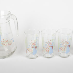 Pichet en verre et quatre verres assortis à décor pastel champêtre, alignés.