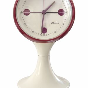 Réveil vintage West Germany de style Space Age, vu de face : cadran blanc à index bordeaux dans une sphère bordeaux, sur pied tulipe blanc.