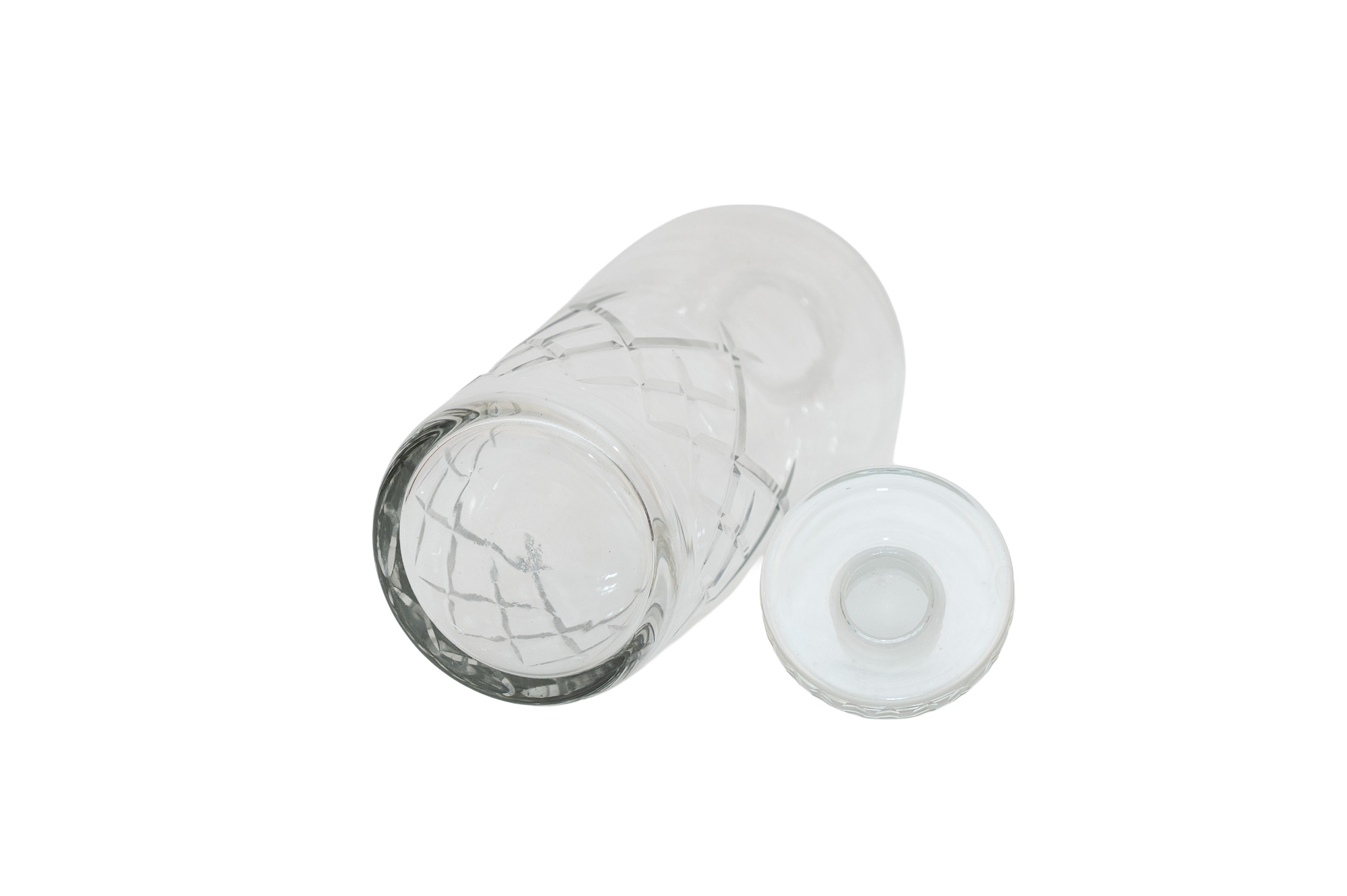 Carafe en cristal couchée sur le côté, avec sa base circulaire au premier plan et le dessous du bouchon visible.