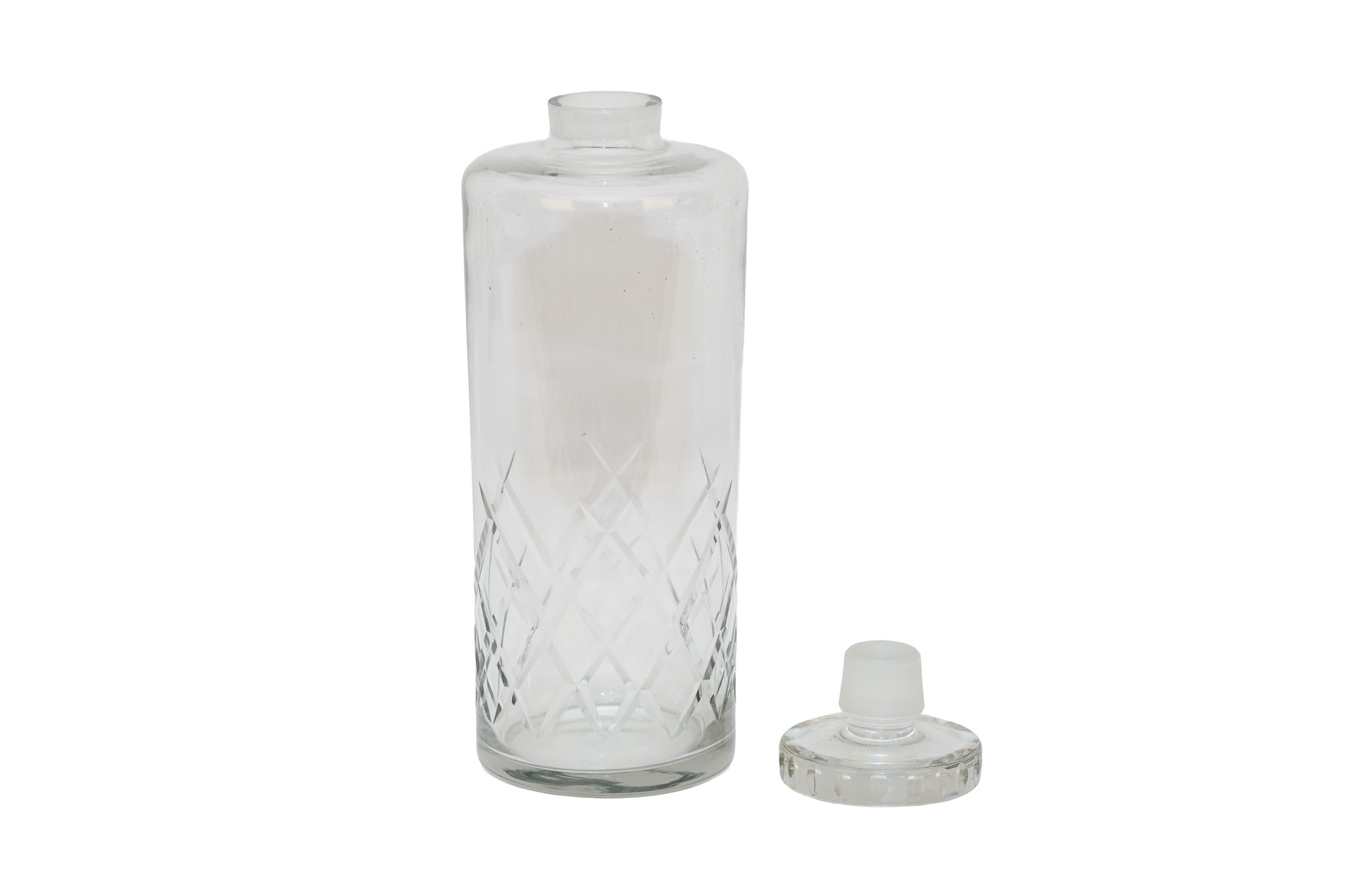 Carafe en cristal taillé présentée debout sans bouchon, avec le bouchon circulaire posé à côté.